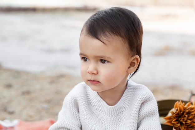 Autunno ritratto di bambina seduta all'aperto indossando casual maglione lavorato a maglia