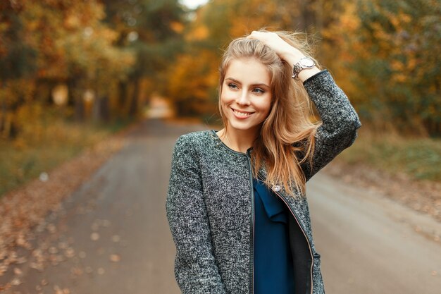 Autunno ritratto di una bella donna felice con un sorriso in abiti alla moda nel parco