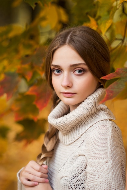 Autunno ritratto di una giovane donna vicino a foglie d'autunno