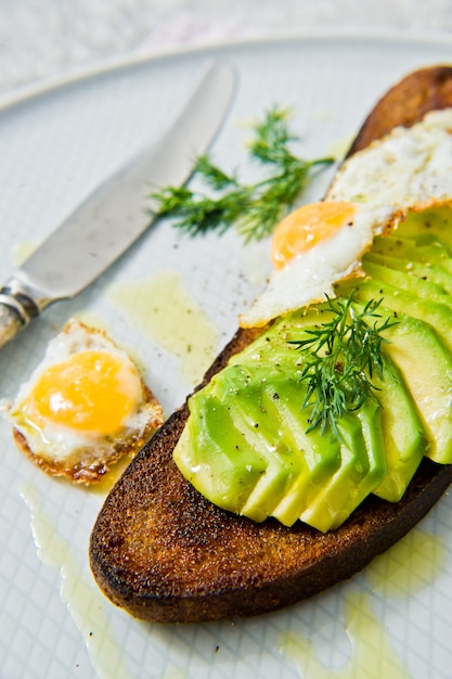 Avacado sandwich con uovo su pane tostato di pane nero.