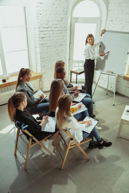 Avanzate. Relatore femminile che dà presentazione in sala al workshop. Centro affari. Veduta dall'alto dei partecipanti tra il pubblico. Evento congressuale, formazione. Istruzione, diversità, concetto inclusivo.