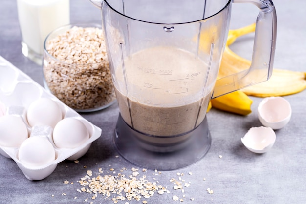 Avena e uova in un frullatore. Frittelle di avena con banana. Processo di cottura graduale. Banane, latte, uova, avena, sale.