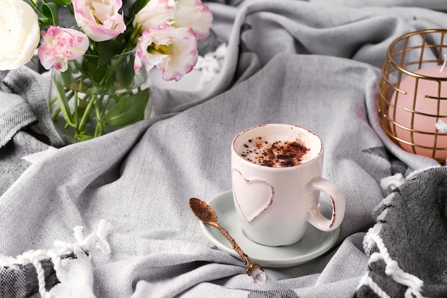 Avere una tazza di caffè con cioccolato, fiori eustoma sulla coperta nel letto.