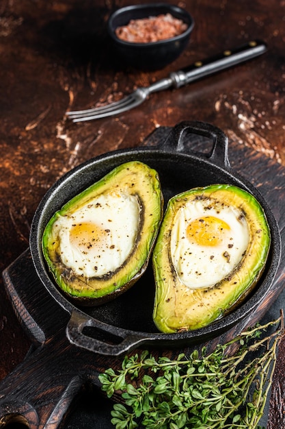 Avocado al forno con uovo sale timo e pepe Sfondo scuro Vista dall'alto