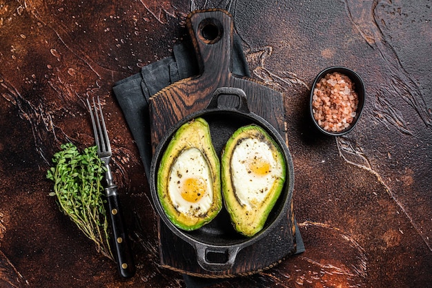 Avocado al forno con uovo sale timo e pepe Sfondo scuro Vista dall'alto