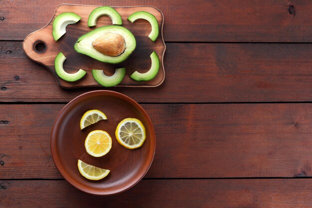 Avocado e limone su tavola di legno Avocado e limone a fette su fondo in legno Cibo vegetariano Copia spazio