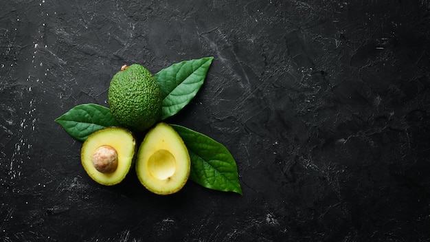 Avocado fresco con foglie su sfondo nero Vista dall'alto Spazio libero per il testo