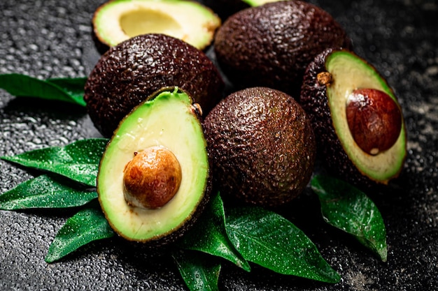 Avocado fresco con foglie su sfondo nero