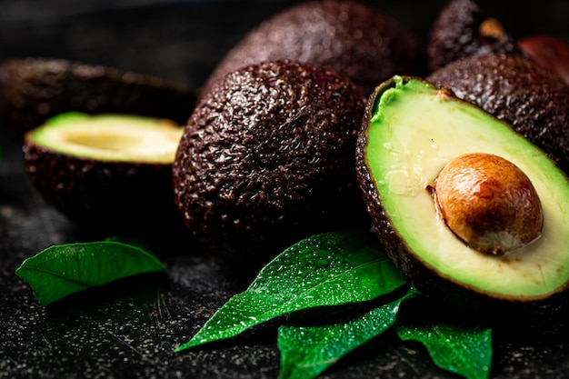 Avocado fresco con foglie su sfondo nero