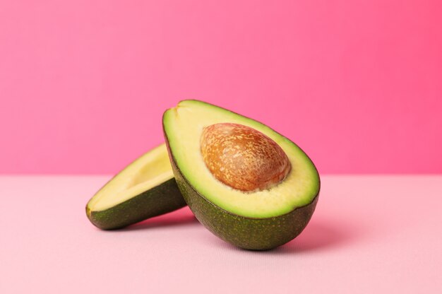 Avocado fresco maturo su fondo rosa, spazio per testo