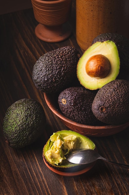 Avocado in un piatto di argilla su uno sfondo di legno scuro e lunatico