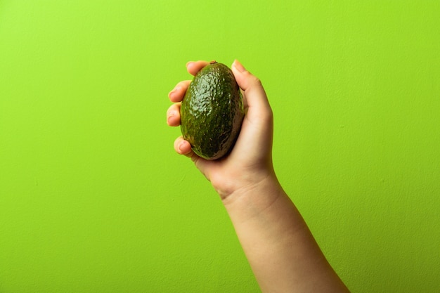 Avocado in una mano di sfondo verde donna