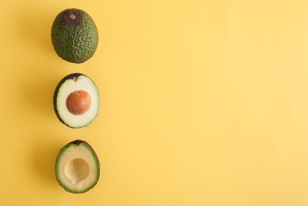 avocado intero e mezzo su sfondo giallo