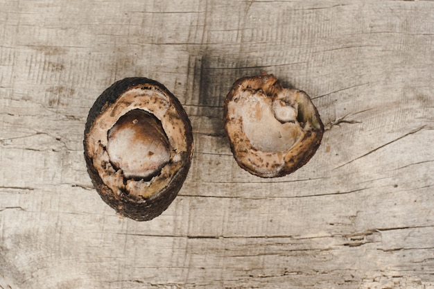 Avocado marcio su fondo di legno. Vecchio avocado ammuffito su tavola di legno. Frutto malsano e disgustoso.