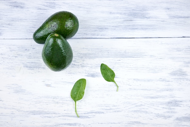 Avocado su fondo di legno bianco con foglie verdi