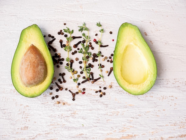 Avocado tagliato a metà su tavola di legno bianco.