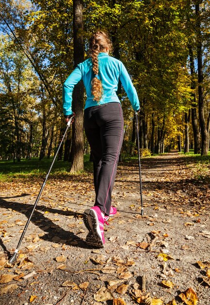 Avventura di nordic walking e concetto di esercizio Donna che fa escursioni con i bastoncini da nordic walking nel parco