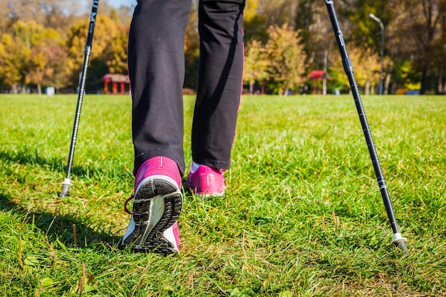 Avventura di nordic walking e concetto di esercizio Gambe da trekking donna e bastoncini da nordic walking nella natura estiva