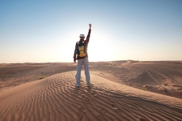 Avventura nel deserto Giovane con zaino che cammina sulla duna di sabbia Dubai Emirati Arabi Uniti