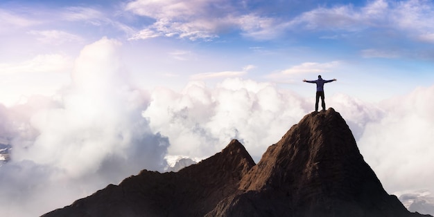 Avventuroso uomo adulto escursionista in cima alle montagne rocciose con le mani aperte