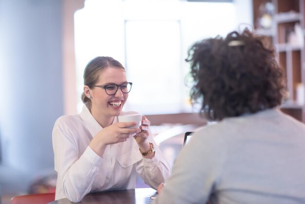 avviare uomini d'affari che utilizzano il laptop che si preparano per la prossima riunione mentre bevono caffè e discutono di idee nell'ufficio creativo