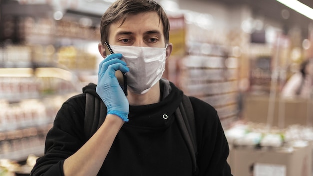 Avvicinamento. giovane con una maschera protettiva che parla sul suo smartphone. igiene e sanità