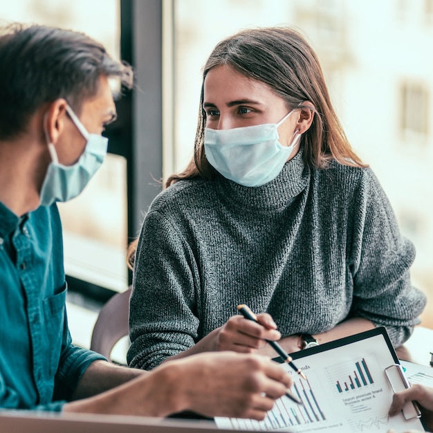 Avvicinamento. giovane donna in una maschera protettiva che parla con il suo collega.