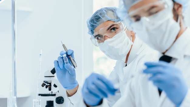 Avvicinamento. gruppo di scienziati in indumenti protettivi che lavorano in laboratorio. foto con copia-spazio.