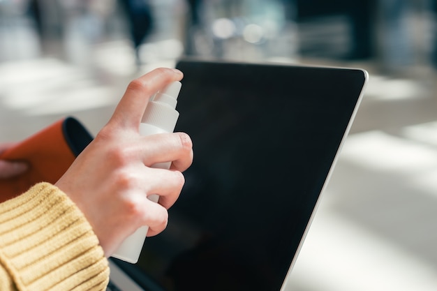 Avvicinamento. la donna che spruzza lo spray sullo schermo del laptop. foto con una copia dello spazio