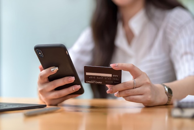 Avvicinamento. mani della donna che tengono smartphone e utilizzano la carta di credito per lo shopping online.