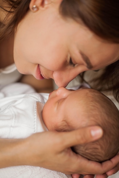 Avvicinamento. Neonato sveglio che dorme tra le braccia della madre. Maternità.