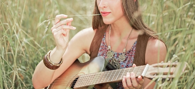 Avvicinamento. ritratto di bella giovane donna hippie con la chitarra che si siede sulla radura della foresta