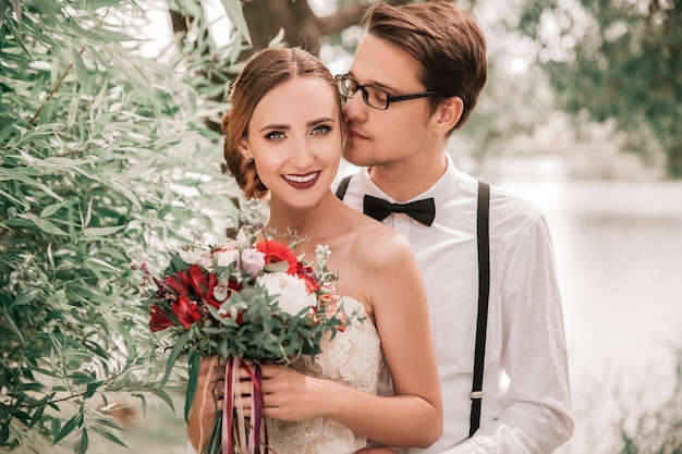 Avvicinamento. sposo felice che bacia la sua sposa nel parco cittadino