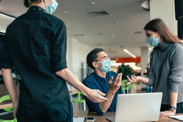 Avvicinamento. team aziendale in maschere protettive che discutono di problemi di lavoro.