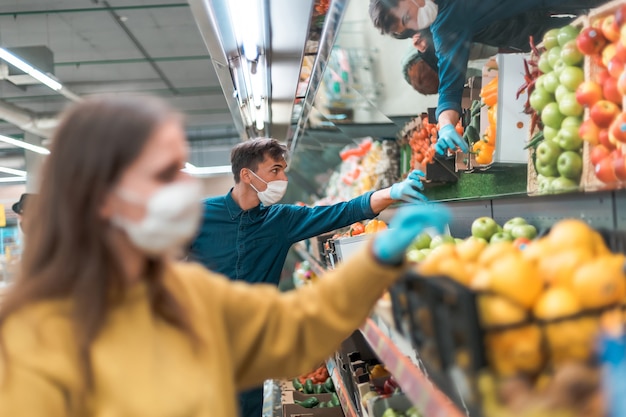 Avvicinamento. uomo con una maschera protettiva in piedi davanti a un banco di frutta