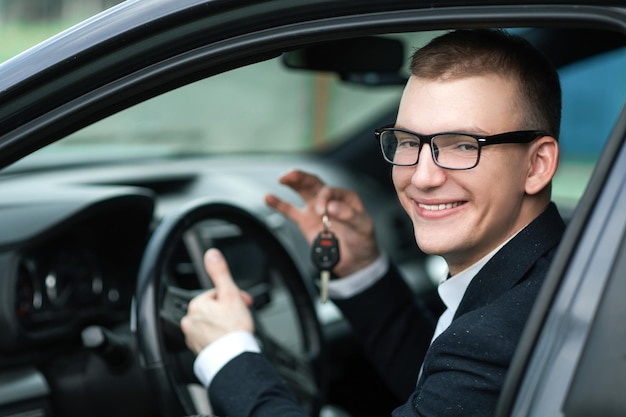 Avvicinamento. uomo d'affari felice che mostra la chiave della sua nuova auto