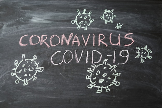 Avviso di epidemia. scritto gesso bianco sulla lavagna in relazione all'epidemia di coronavirus in tutto il mondo. Covid 19 pandemia Testo su sfondo nero con spazio libero. batteri virali disegnati