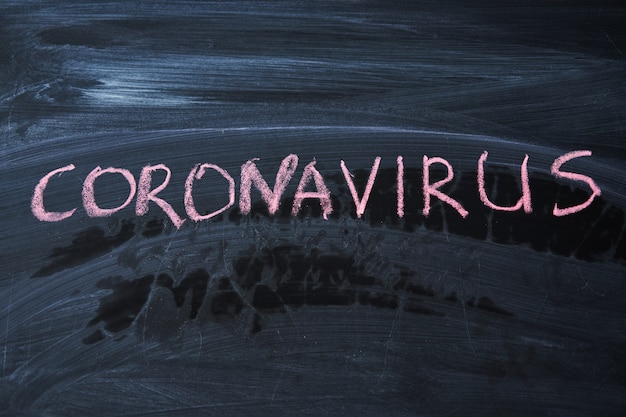 Avviso di epidemia. scritto gesso bianco sulla lavagna in relazione all'epidemia di coronavirus in tutto il mondo. Covid 19 pandemia Testo su sfondo nero con spazio libero.