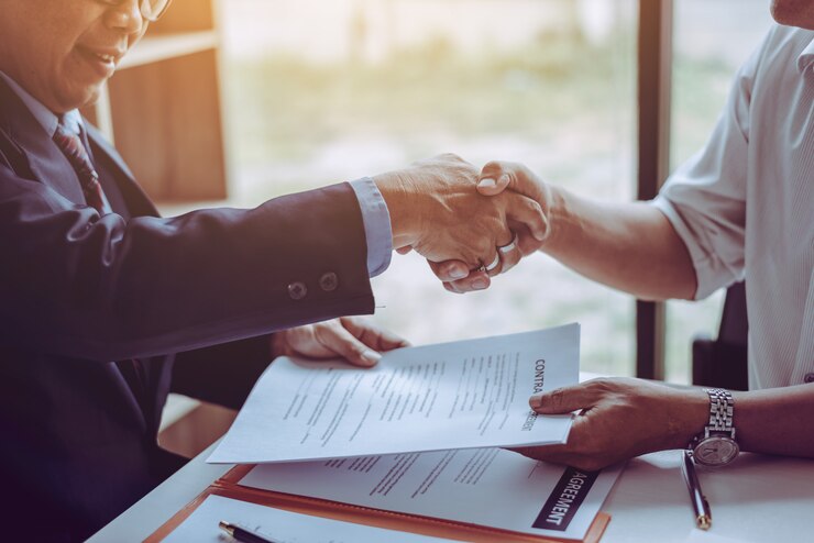 Avvocati di mezza età asiatici avvocati che si stringono la mano dopo aver discusso di un contratto concluso.