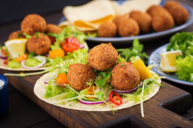 Avvolgere la tortilla con falafel e insalata fresca. Tacos Vegani. Cibo vegetariano sano.