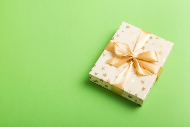 Avvolto Natale o altre festività regalo fatto a mano in carta bianca con nastro dorato su sfondo colorato Decorazione della scatola regalo di regalo su tavolo colorato vista dall'alto con spazio per la copia