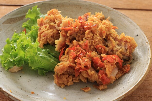 Ayam Geprek è il cibo di strada popolare in Indonesia. Fatto da pollo croccante schiacciato in Sambal Bawang (salsa di peperoncino e aglio). Servito con Riso e Verdure