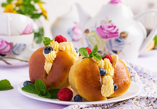 Babà al rum decorato con panna montata e lampone fresco, mirtillo. Savarin con rum, panna e frutti di bosco. cucina italiana