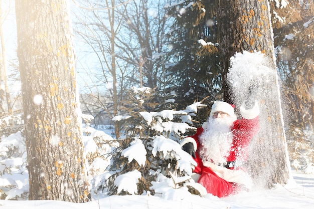 Babbo Natale arriva con i regali dall'esterno. Babbo Natale in abito rosso con barba e occhiali sta camminando lungo la strada per Natale. Babbo Natale porta i regali ai bambini.