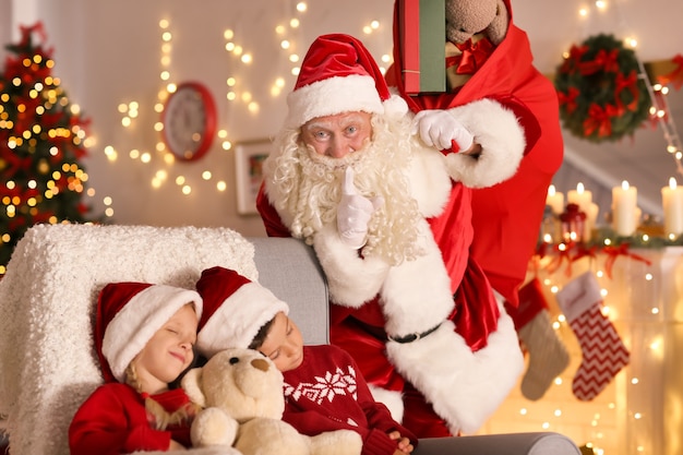 Babbo Natale autentico vicino a bambini addormentati in camera con bellissime decorazioni natalizie