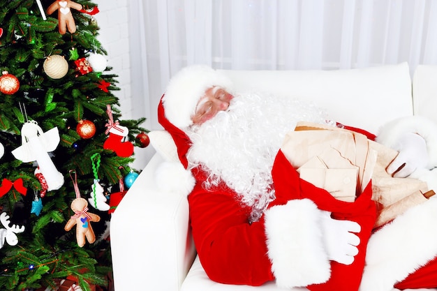 Babbo Natale che dorme a casa vicino all'albero di Natale