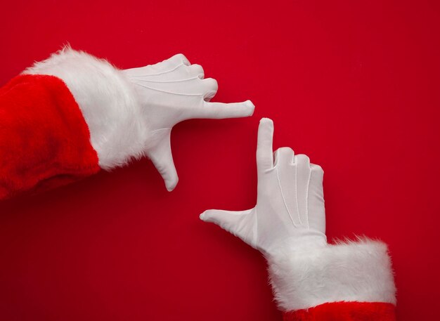 Babbo Natale che fa cornice con la mano su sfondo rosso con spazio per la copia