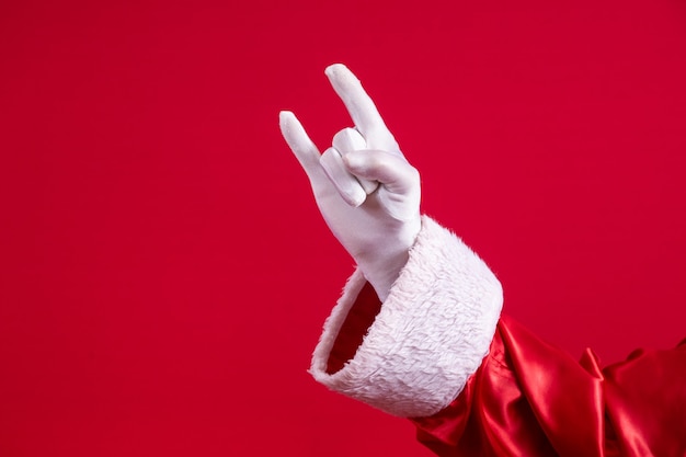 Babbo Natale che fa il segno del rock n roll con le mani e lo sfondo rosso.