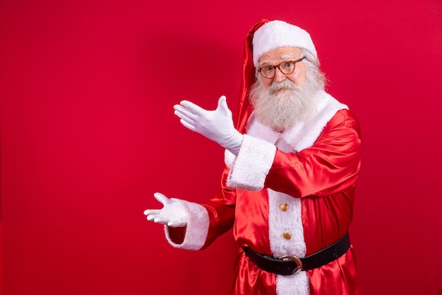Babbo Natale che indica da parte, pubblicità promozione natalizia, annuncio sconto Natale Capodanno isolato su sfondo rosso.