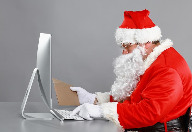 Babbo Natale che legge le lettere dei bambini e scrive loro le risposte utilizzando il laptop.